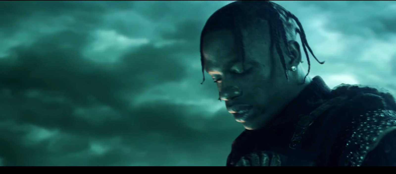 a man with dreadlocks standing in front of a cloudy sky