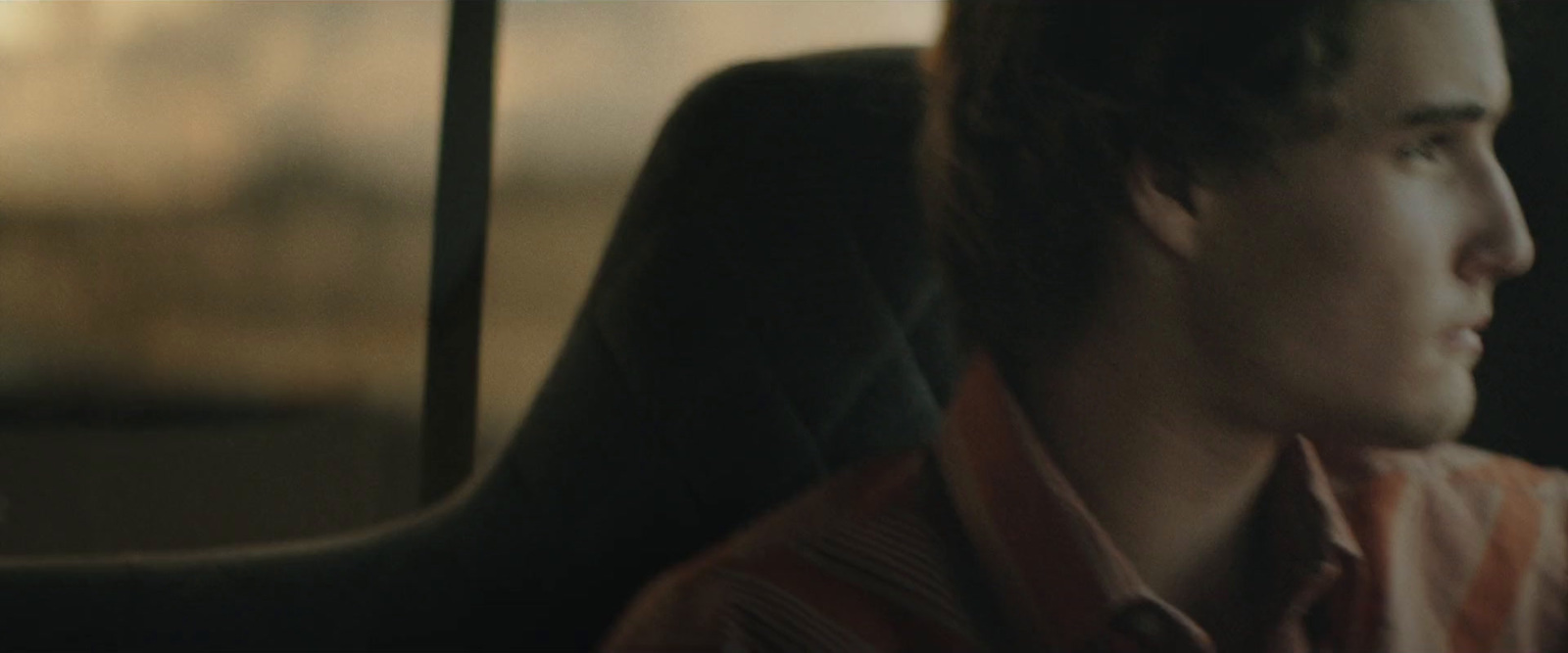 a young man sitting in a car looking out the window