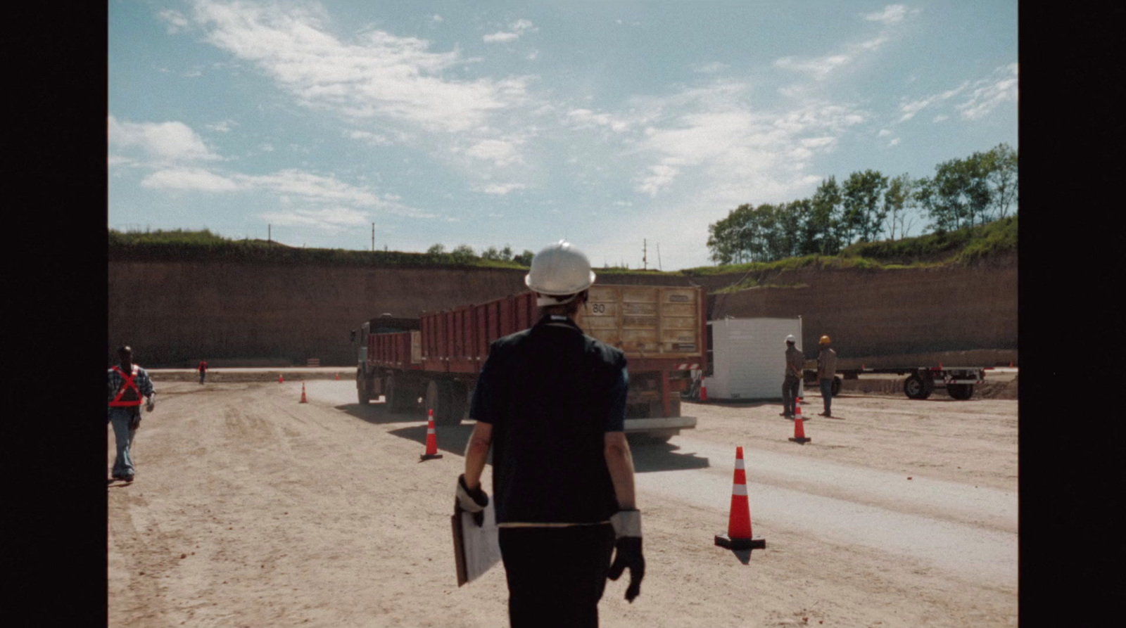 a man in a hard hat walks down a dirt road