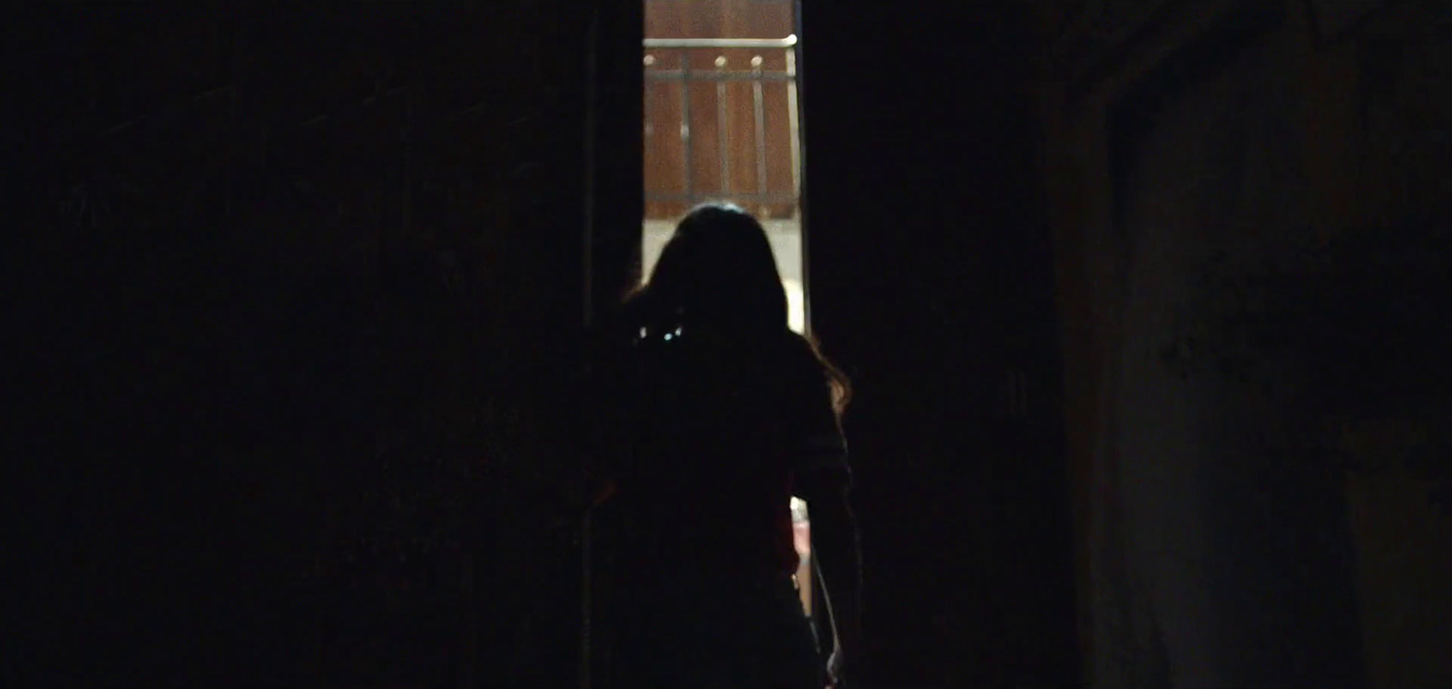 a woman standing in a dark hallway with a cell phone to her ear