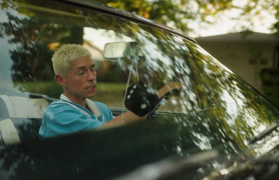 a man sitting in a car with his hand on the steering wheel