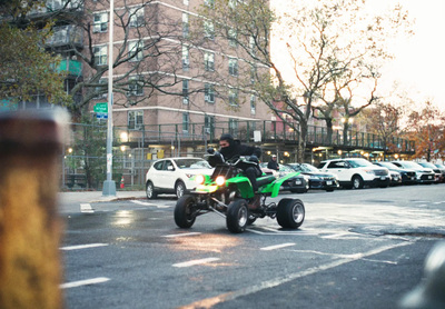 a man riding a green motorcycle down a street