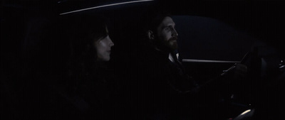 a man and a woman sitting in a car at night