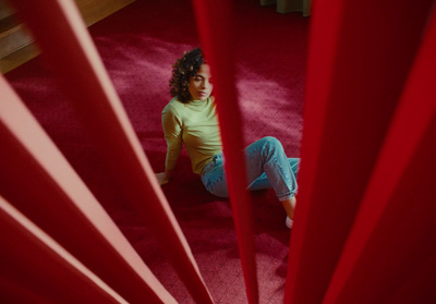 a woman sitting on the floor in front of a red curtain