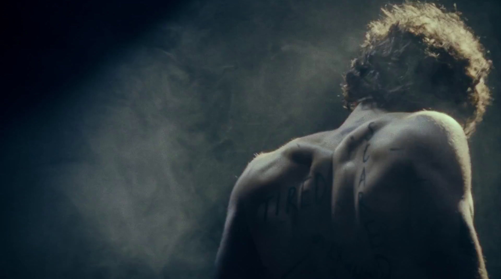 a man with no shirt standing in the smoke