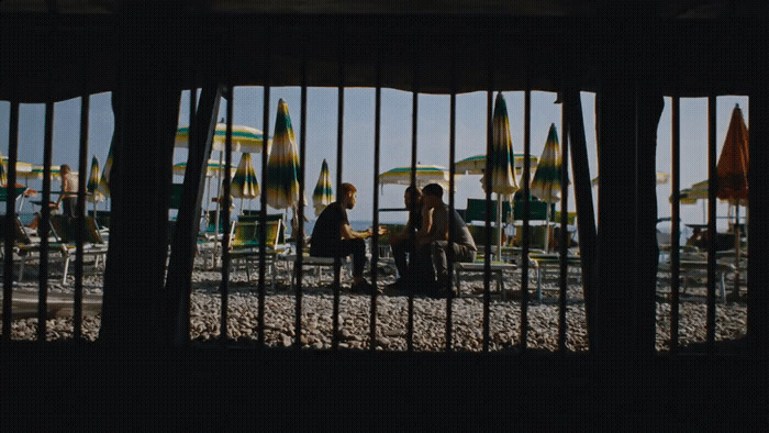 a group of people sitting at a table in front of umbrellas