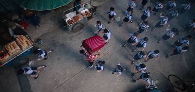 a group of people walking down a street next to a food cart