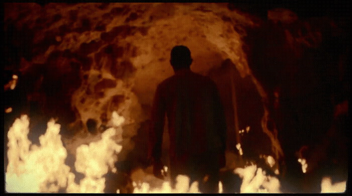 a man standing in front of a fire filled cave