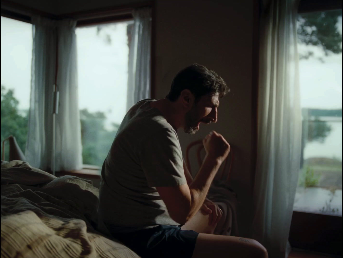 a man sitting on a bed in front of a window