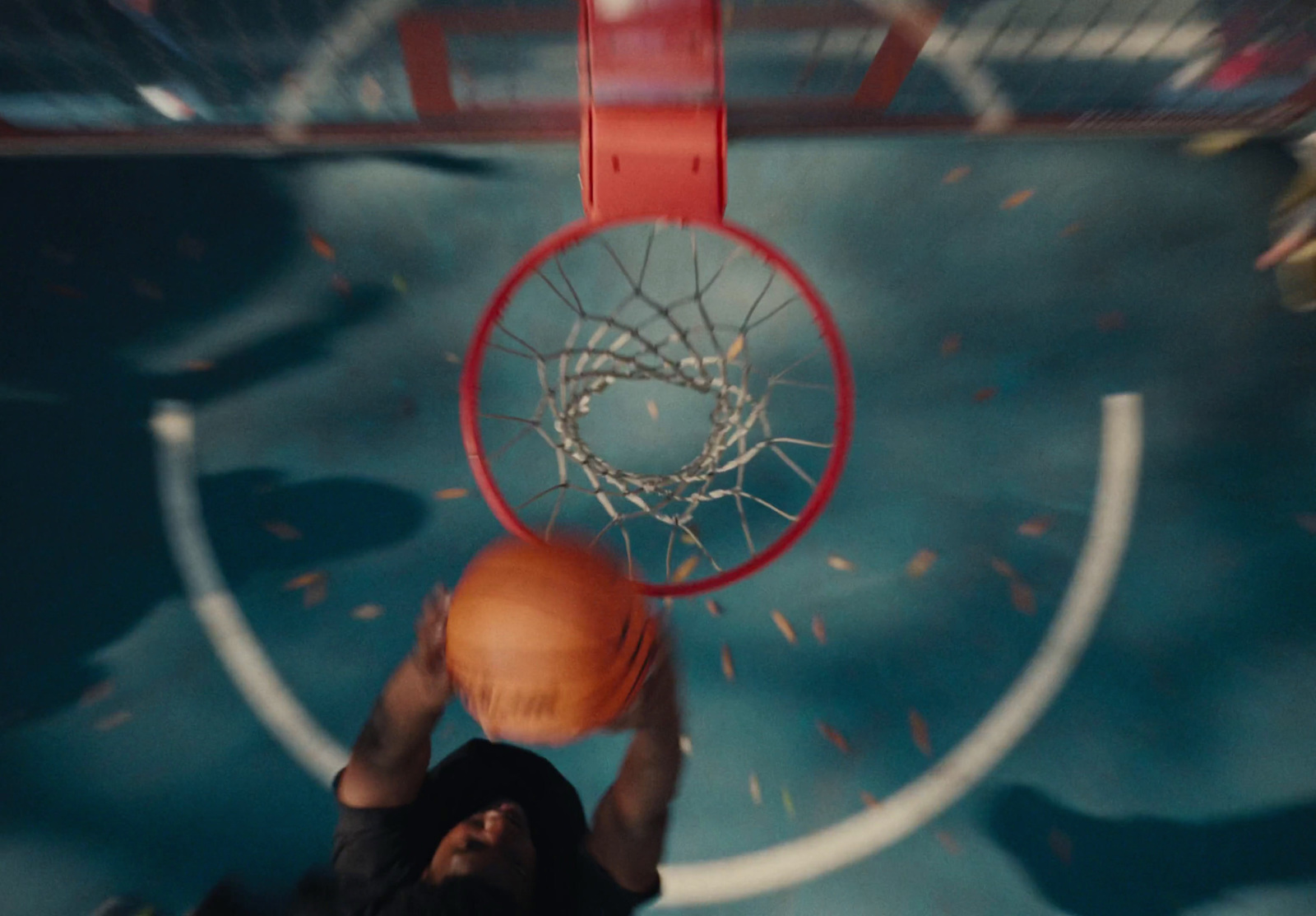 a man holding a basketball up to the rim of a hoop