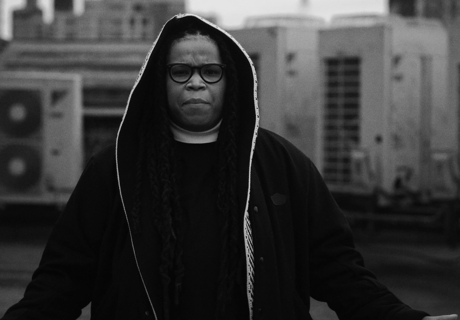 a woman in a hoodie standing in front of a building