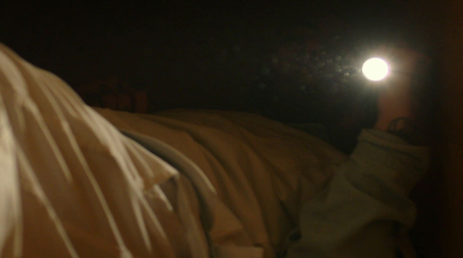 a person laying in bed with a flashlight in their hand