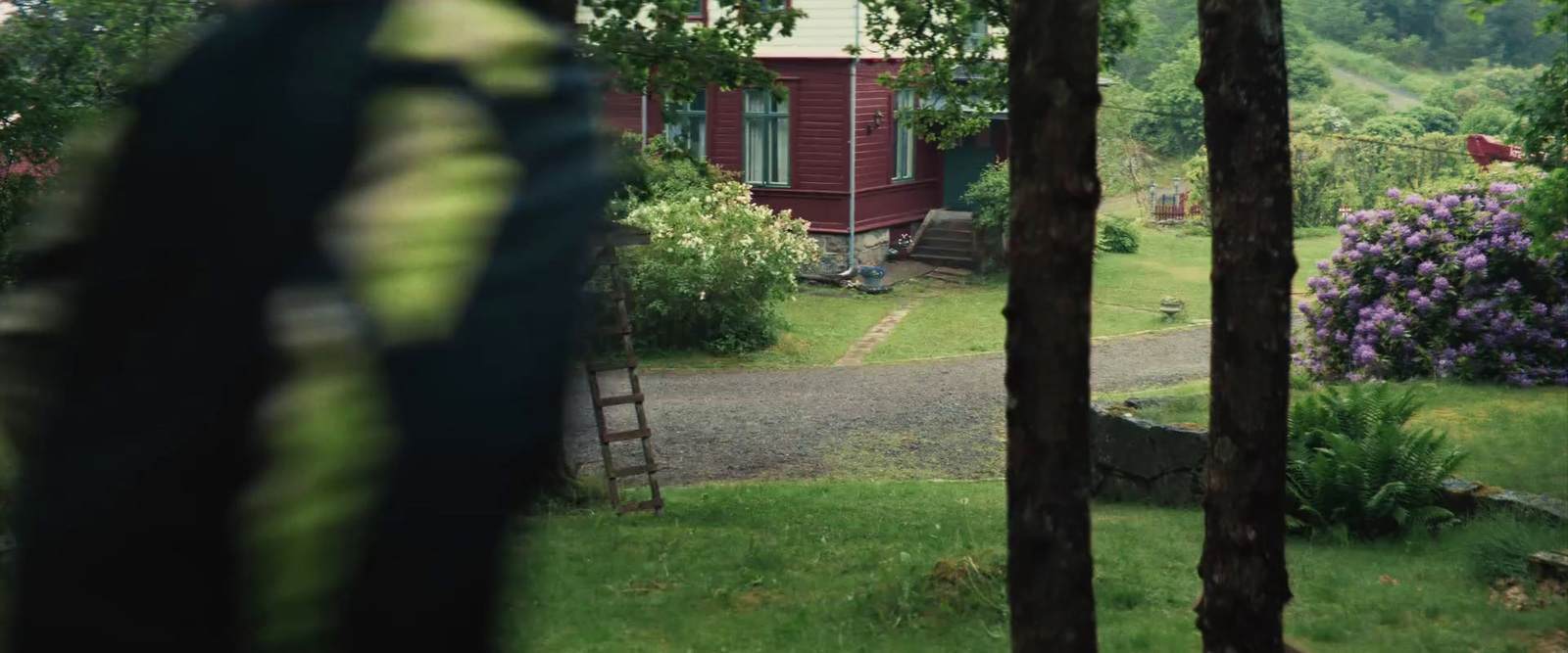 a red house in the middle of a lush green field