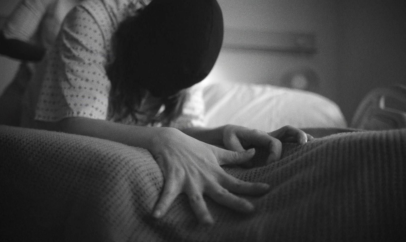 a woman laying in bed with her hand on the pillow