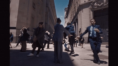 a group of people walking down a street next to tall buildings