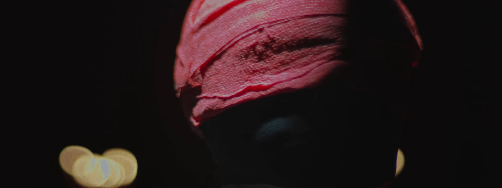 a woman wearing a pink turban in the dark