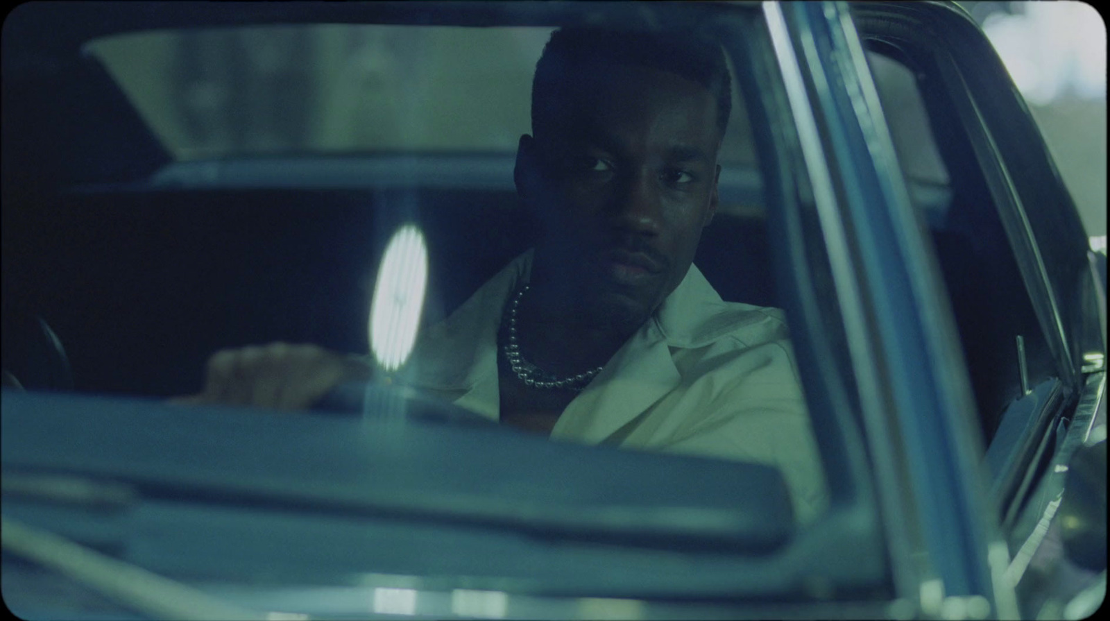 a man sitting in a car with his hand on the steering wheel