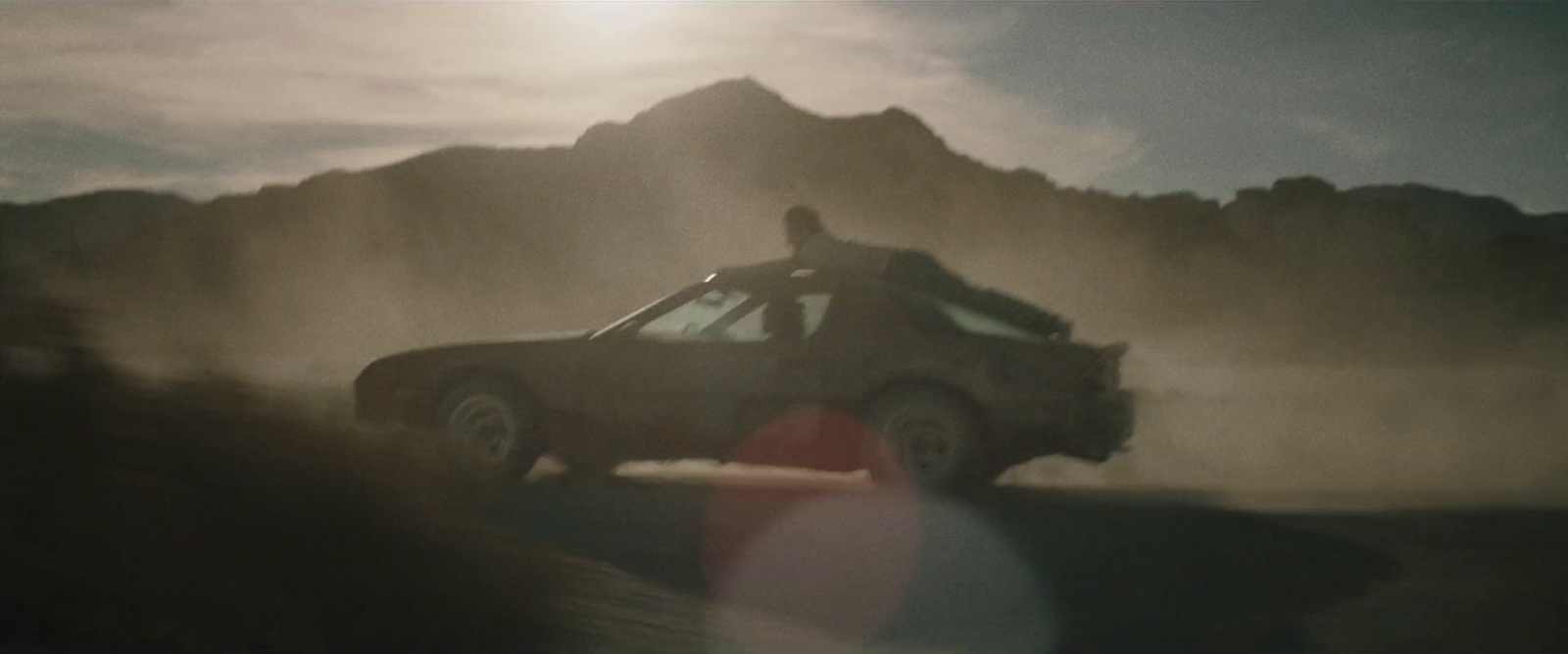 a man riding in the back of a truck on a dirt road