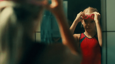 a young girl looking into a mirror with her hands on her head