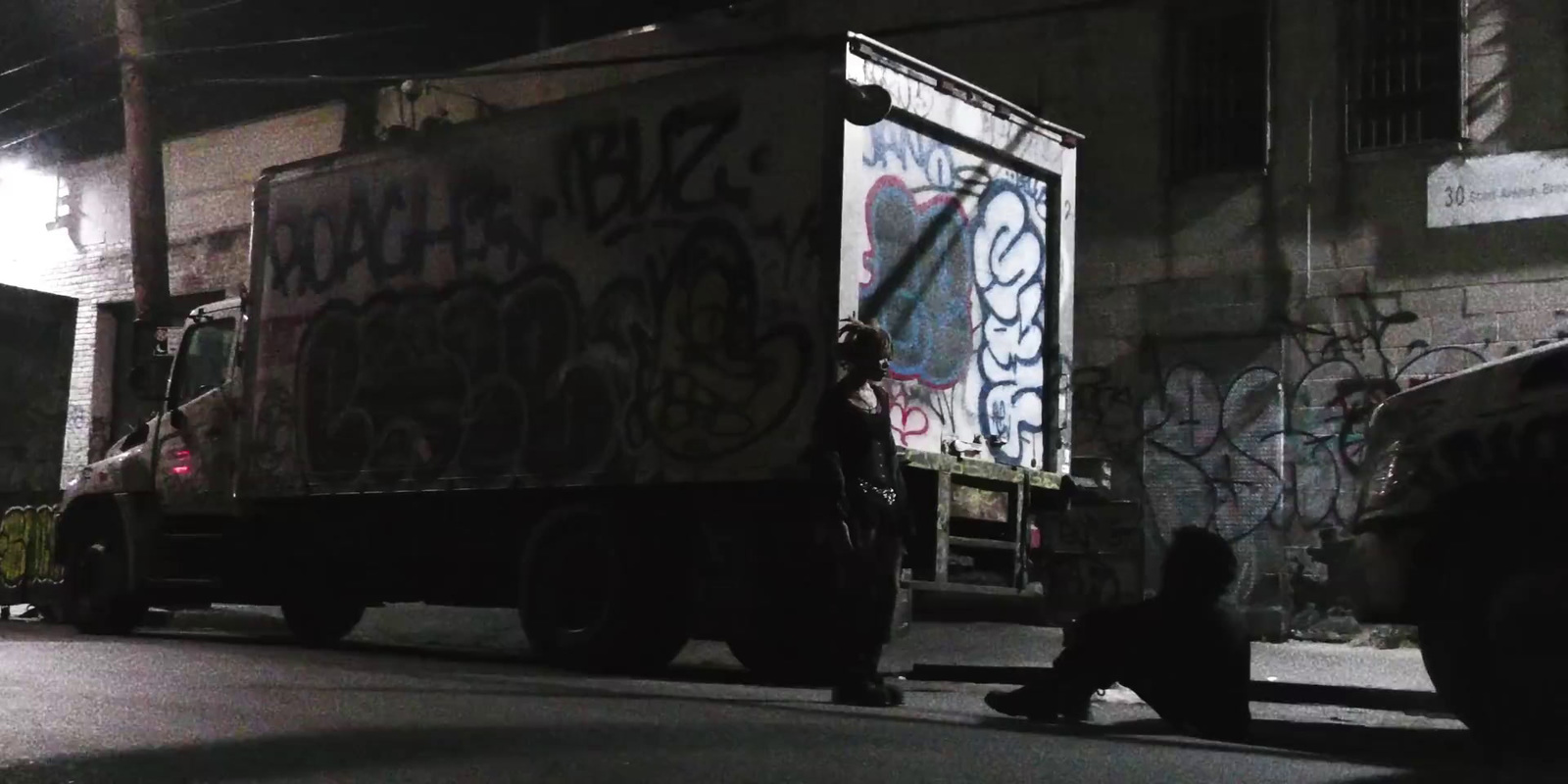 a man sitting on the side of a road next to a truck