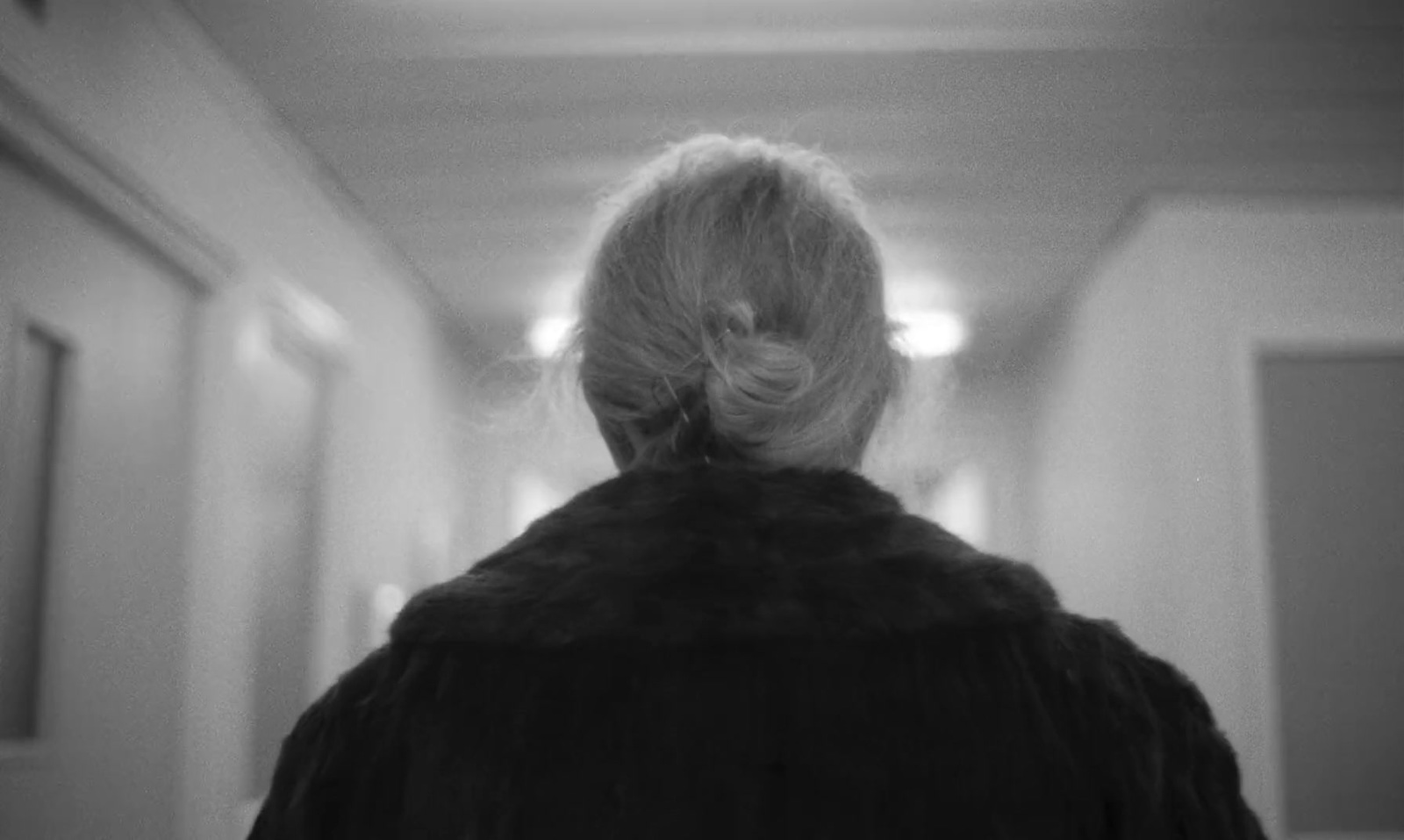 a woman walking down a hallway in a black and white photo