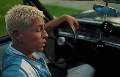 a man driving a car with his hand on the steering wheel