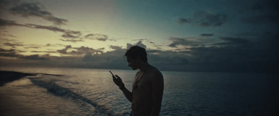 a man standing on a boat looking at his cell phone