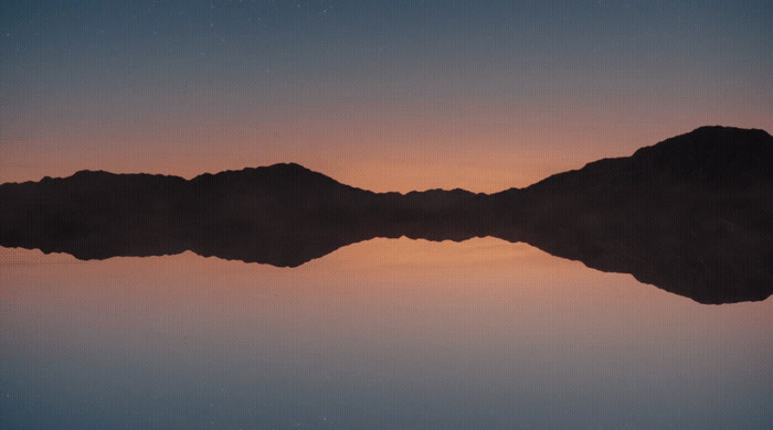 a large body of water with a mountain in the background