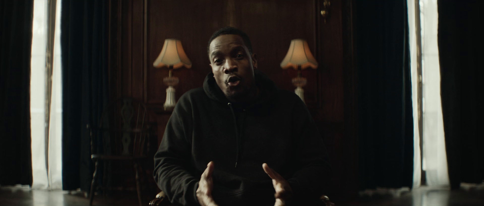 a man in a black hoodie sitting in a room