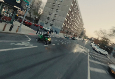 a motorcycle driving down a street next to tall buildings