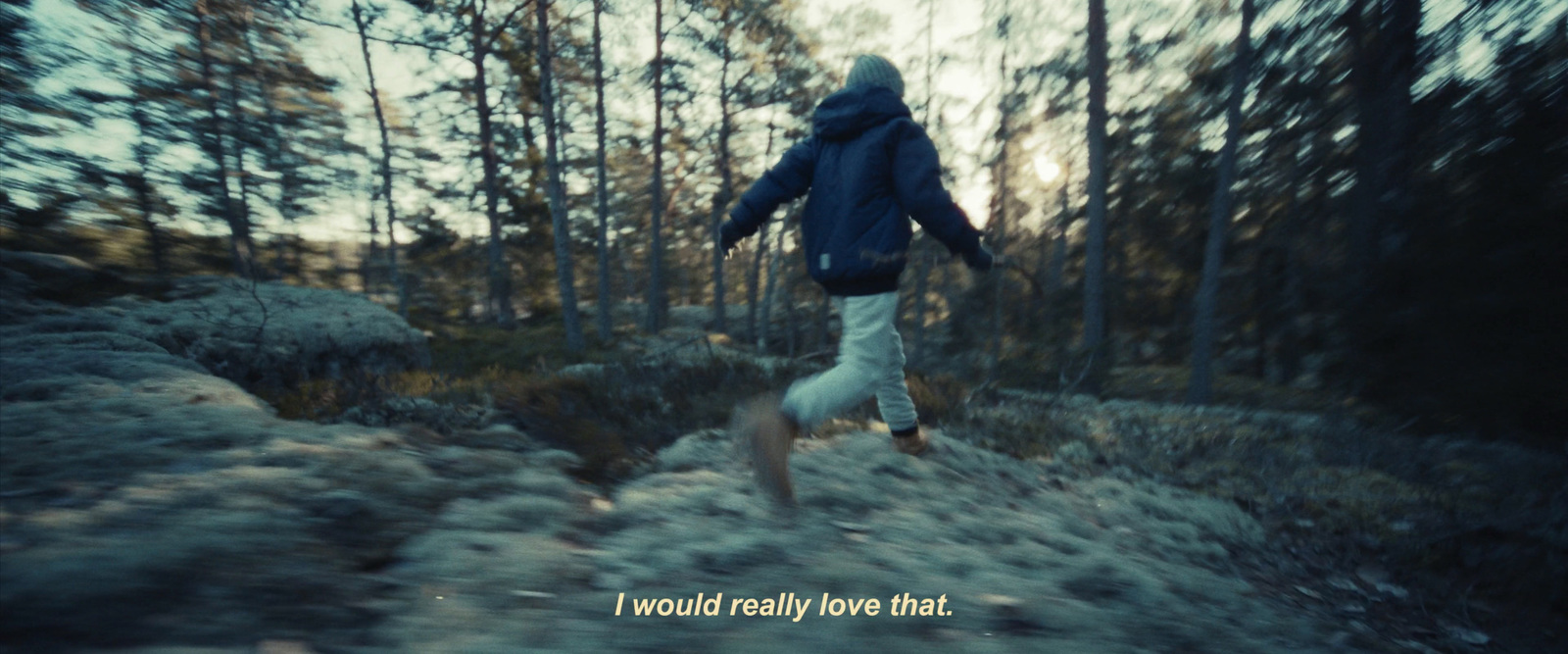 a person in a blue jacket is running through the woods