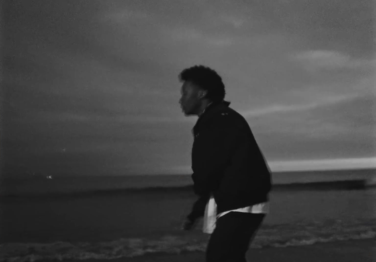 a man walking along a beach next to the ocean