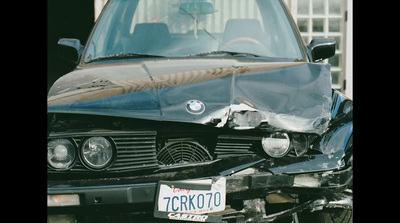 the front of a black car with a dented hood