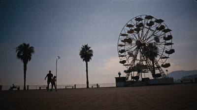 a man standing next to a ferris wheel on a beach