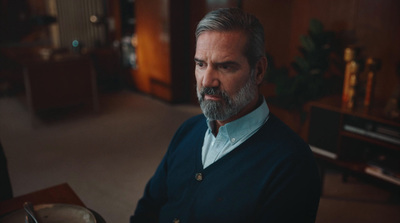 a man with grey hair and a beard wearing a blue sweater