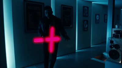 a man standing in a hallway holding a neon cross