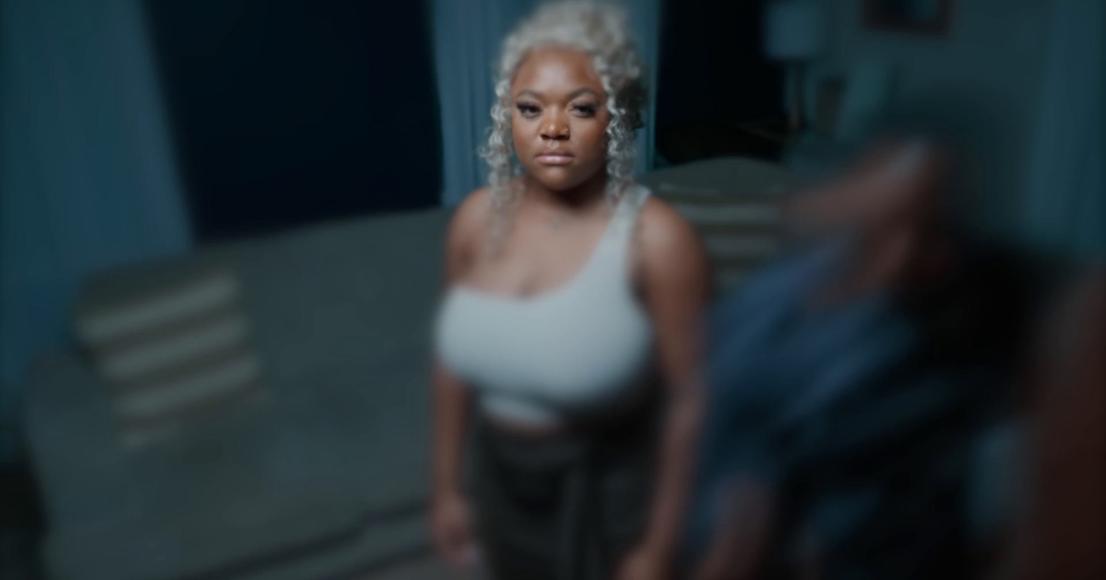 a woman in a white tank top standing in a room