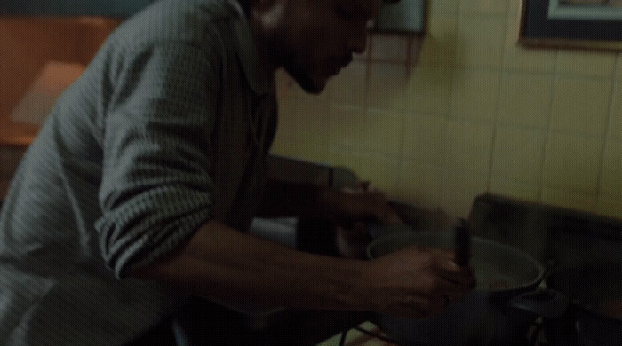 a man standing over a pot in a kitchen