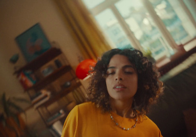 a woman with curly hair wearing a yellow shirt