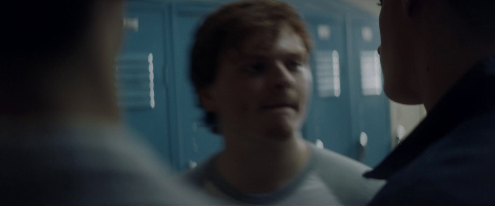 a man standing in front of lockers talking to another man