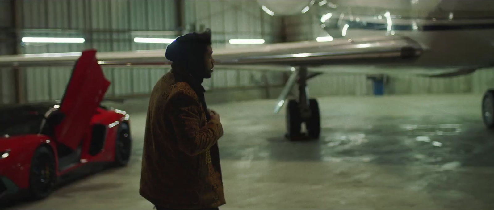 a man standing next to a red car in a garage