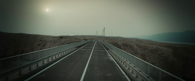 a road going through a desert with a hill in the background