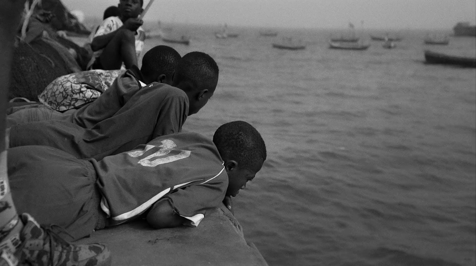 a black and white photo of people sitting on a pier