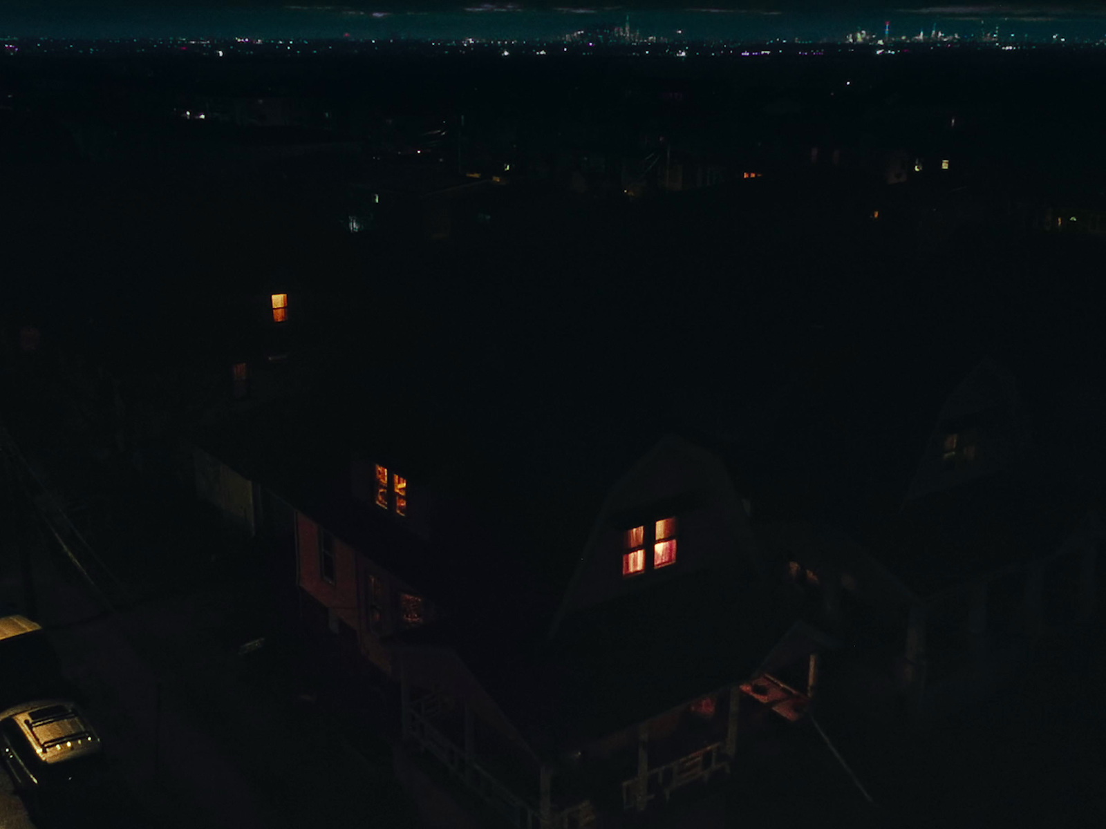 a night time view of a house with a car parked in front of it