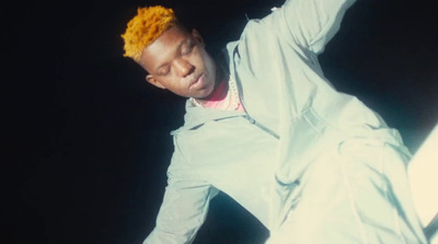 a man with a yellow mohawk standing in front of a black background