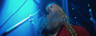 a bearded man singing into a microphone on stage