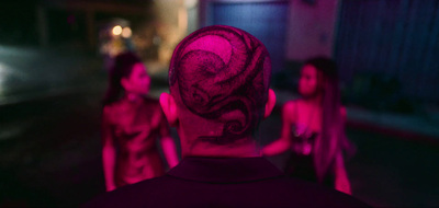 a man with a tattoo on his head standing in front of a group of other