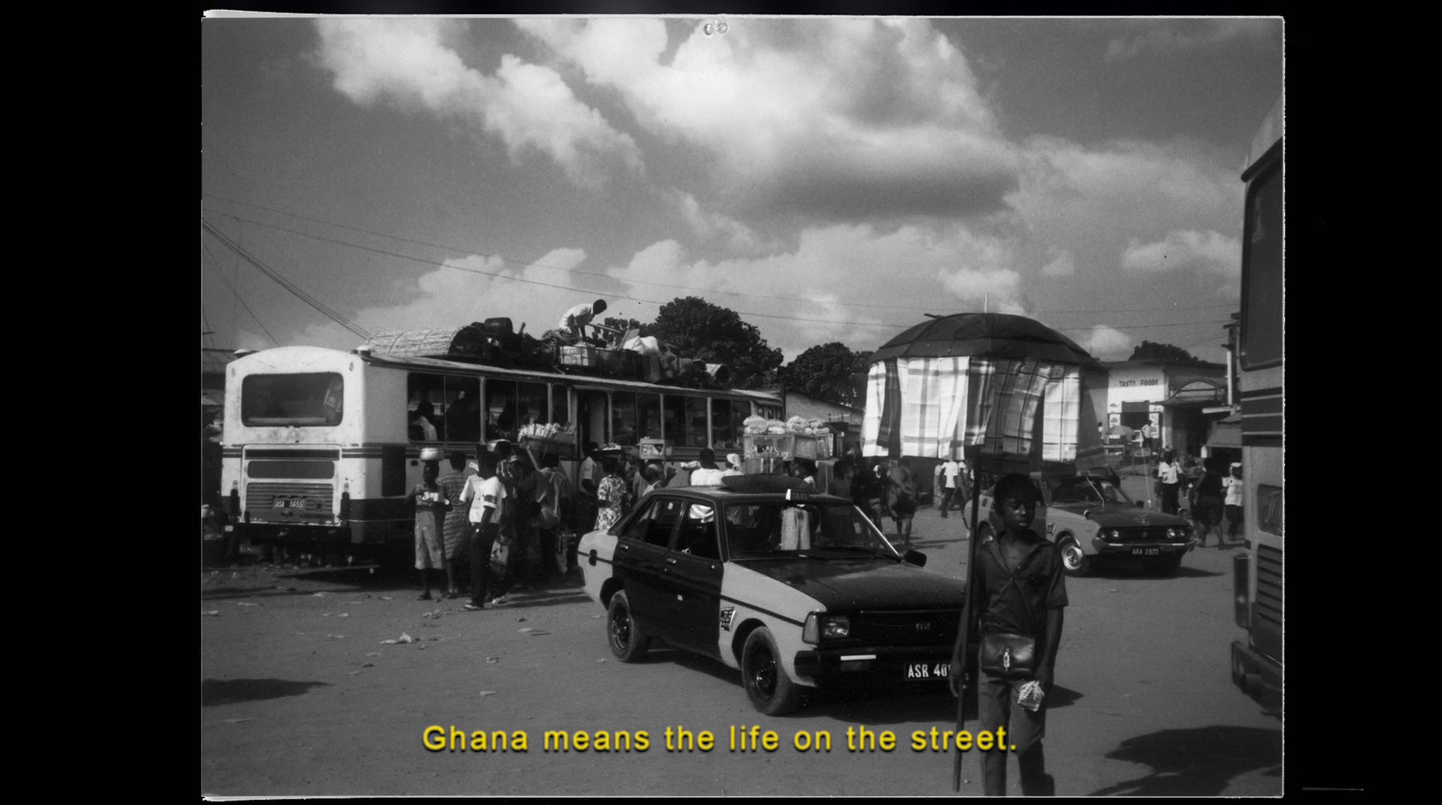 a black and white photo of a street scene with people and vehicles