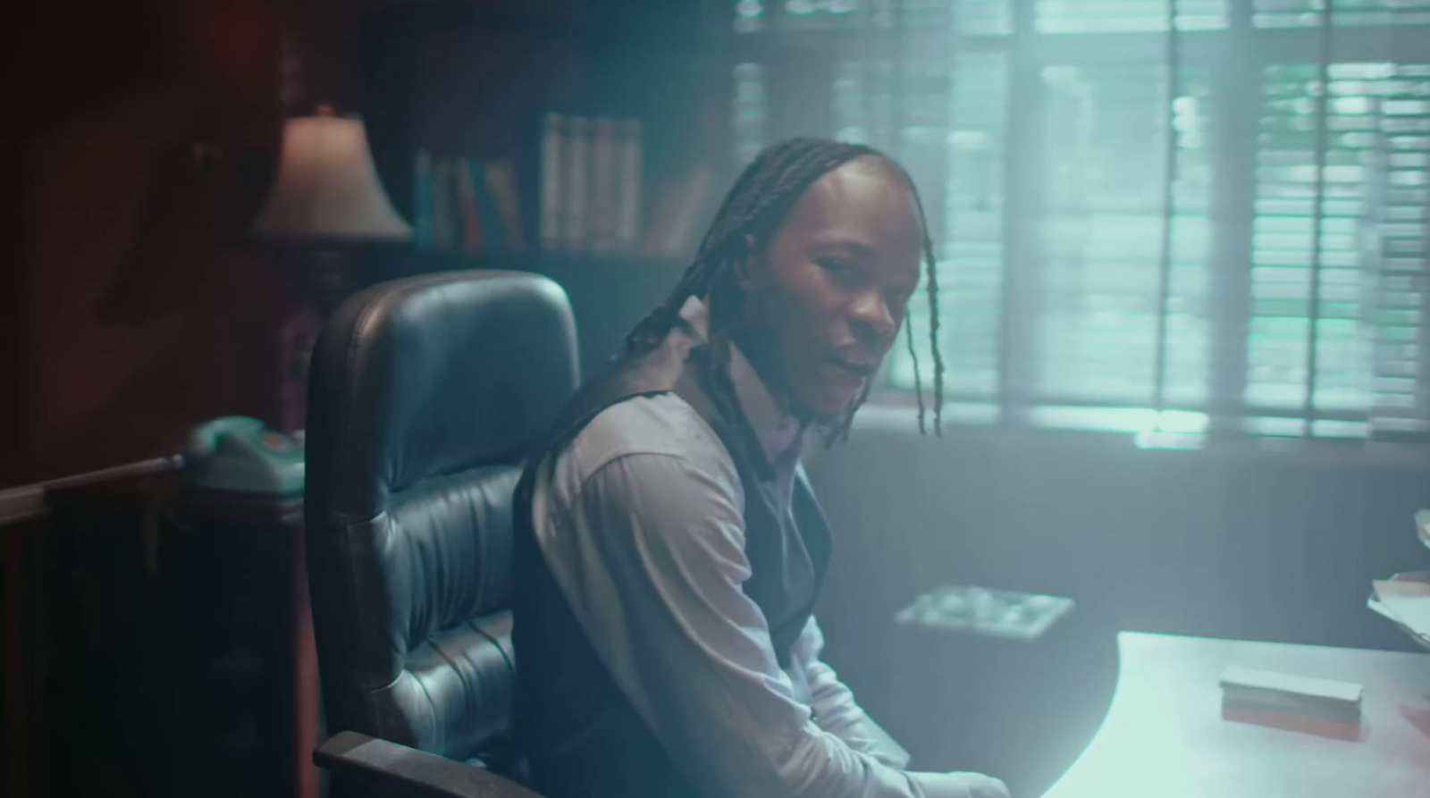 a man with dreadlocks sitting at a desk