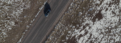 an aerial view of a car driving down a snowy road